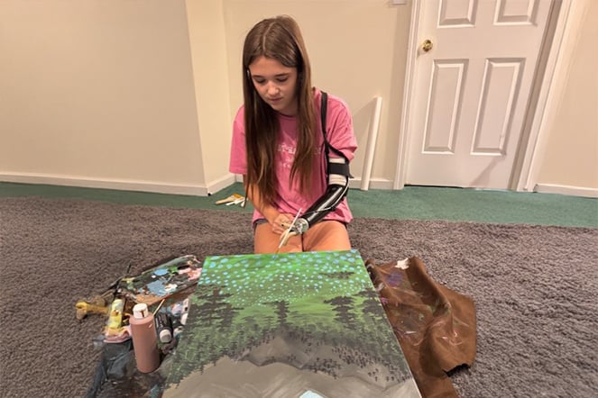 a child with a prosthetic arm painting on a campus