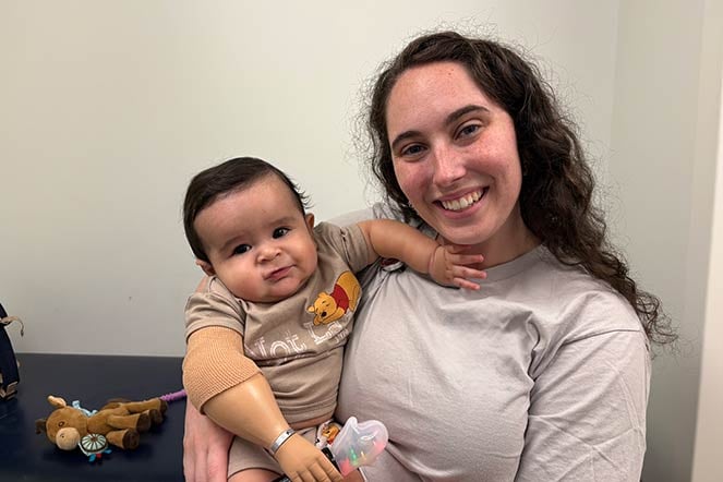 prosthetist-orthotist holds baby with limb difference
