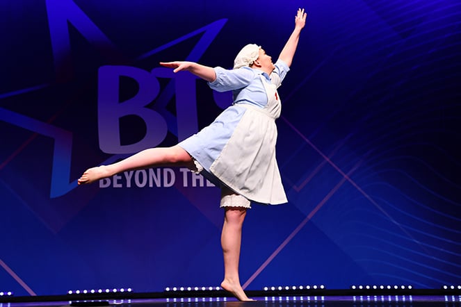 a teenager in costume jumping during a dance performance