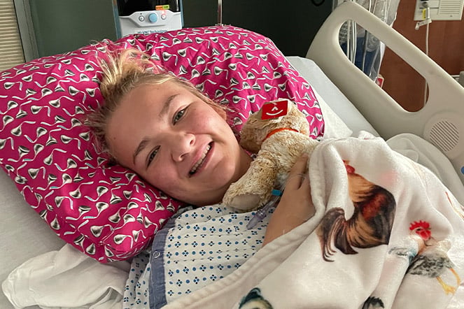 a smiling child lying in a hospital bed