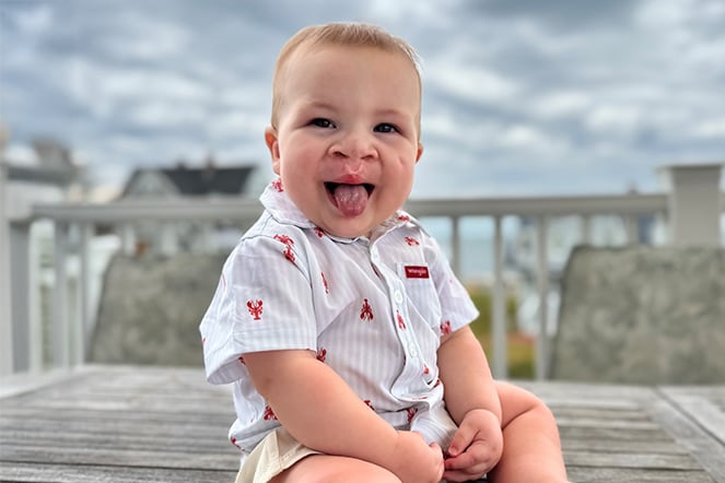 a smiling baby on a boardwalk near the beach