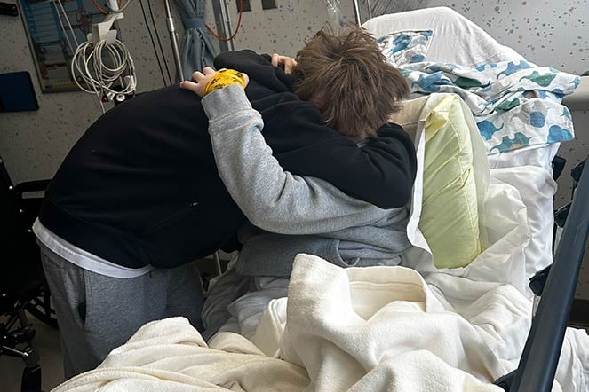 twin brothers hug in hospital bed
