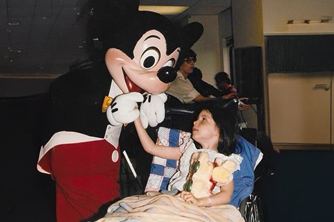 a child in a wheelchair meeting a Mickey Mouse costumed-performer