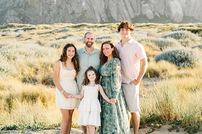 a family portrait of a mother and father with their son and two daughters in front of a large pasture