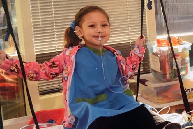 a child sitting in a swing in a hospital room