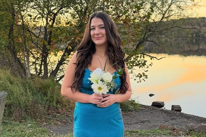 a child holding a bouquet of flowers next to a lake