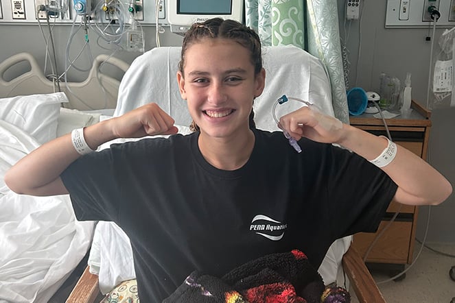 a child flexing her arms in a hospital room