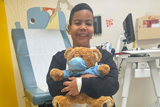 a patient hugging a teddy bear wearing a mask