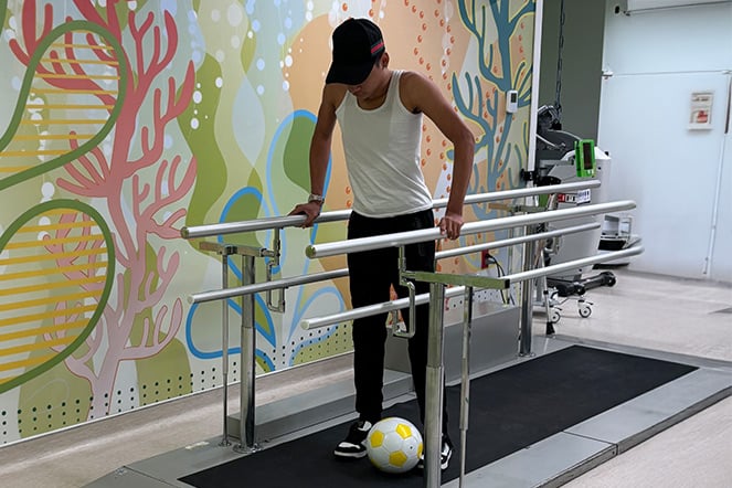 a child preparing to kick a soccer ball during a physical therapy session