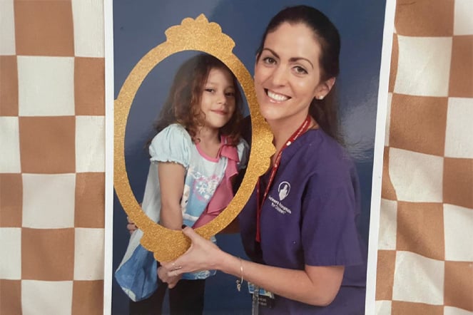 a woman in scrubs holds a child and a picture frame