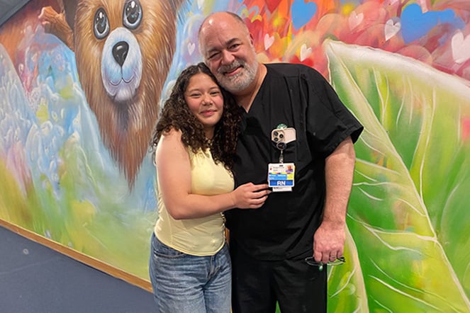 a man and teenager sharing a hug in front of a mural