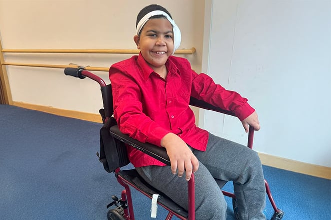 a child smiling while sitting in a wheelchair