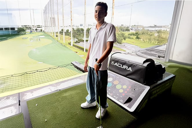 a child holding a golf club at a driving range