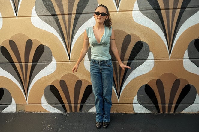 female teen toe walking patient in front of large mural