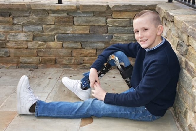 a child wearing a leg brace smiles as he sits of the floor