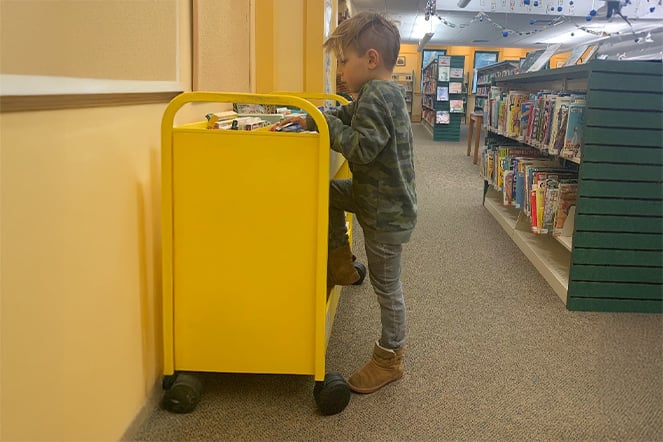 Aksel at a book cart in a library.