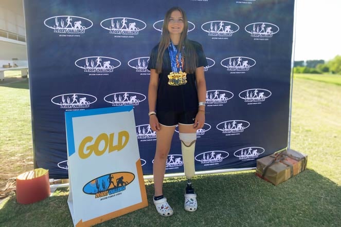 Ali wearing several medals, sign next to her says "Gold"