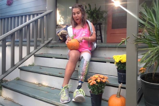 Aleia on a porch carving a pumpkin.