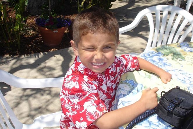 a child in a Hawaiian shirt smiling at a picnic table