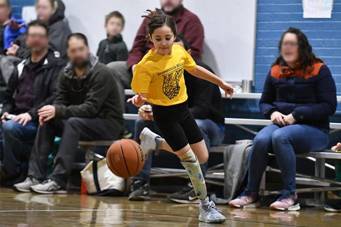 patient wearing a prosthetic playing basketball as fans cheer 