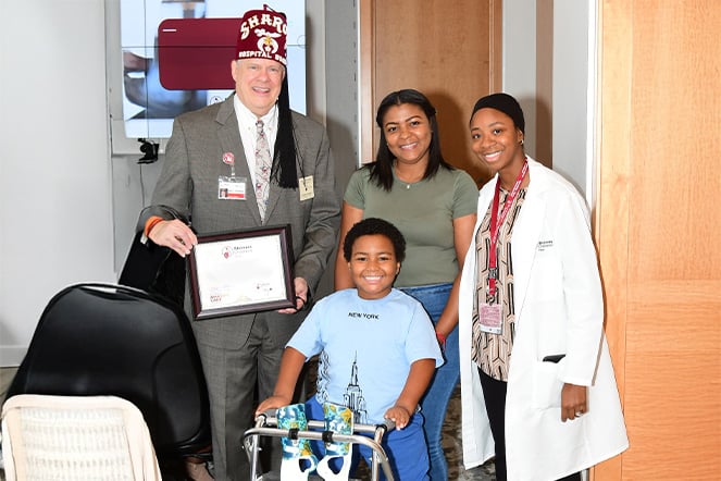 a child with a walker smiling with three adults 