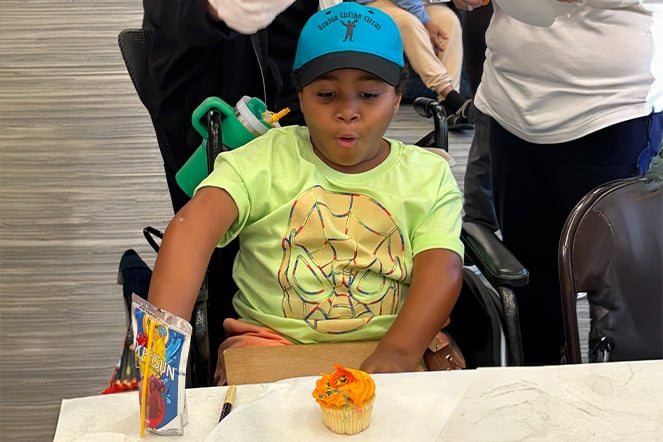 an excited child in a wheelchair sitting in front of a cupcake