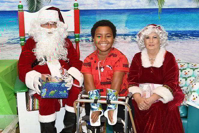 a child with arm casts seated between Mr. and Mrs. Claus