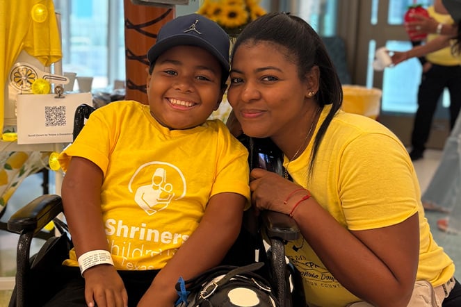 an adult woman kneeling next to a child in a wheelchair
