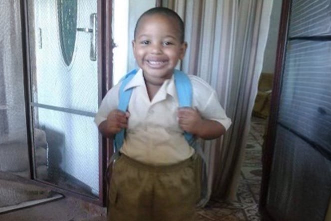 a vintage photo of a young child smiling and wearing a backpack