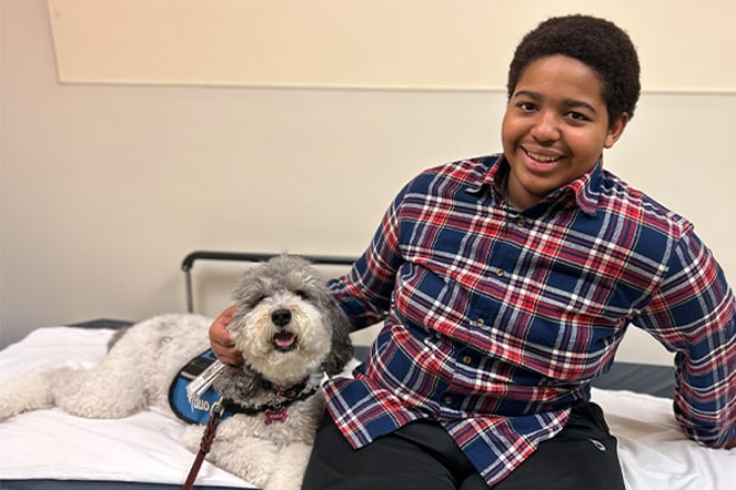 a teenager with a small dog smiling on an examination table