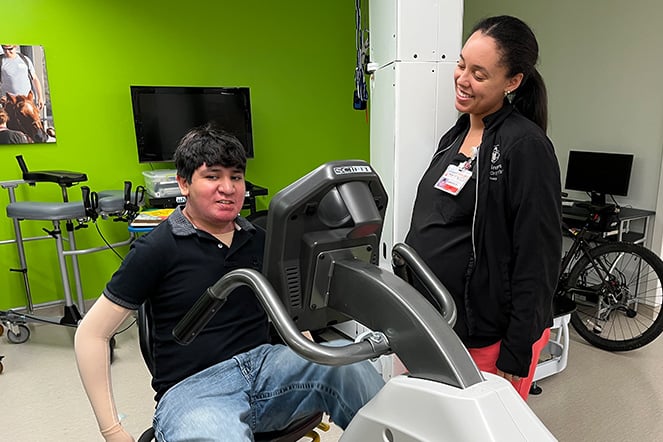 an adult smiling at a child on a stationary bike