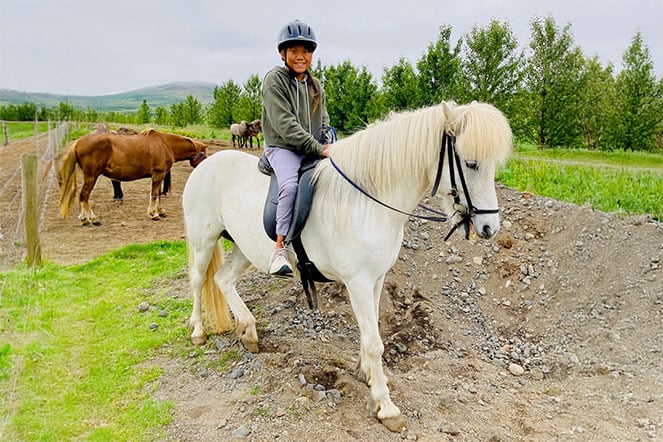 a child wearing a helmet riding a horse