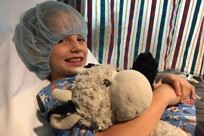 burn patient wearing a hair net holding a large cow plushie