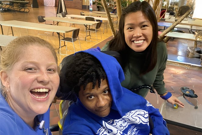 two adults take a selfie photo with a child in a hooded sweatshirt