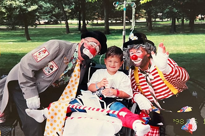 a vintage photo of a child smiling in between two clowns