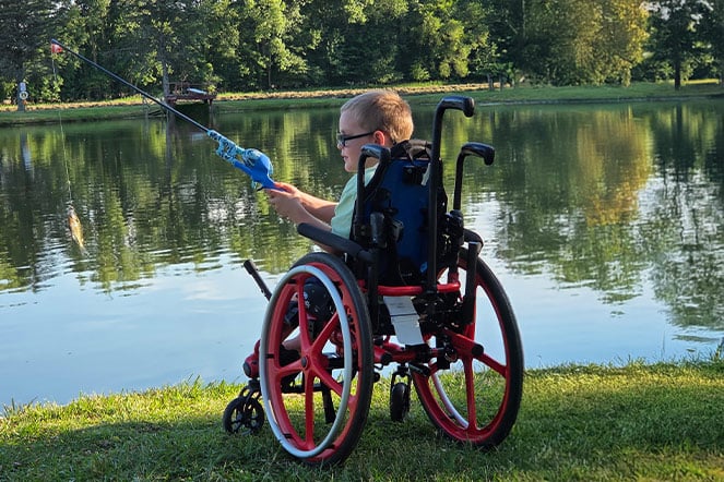 a child in a wheelchair fishing on a lake
