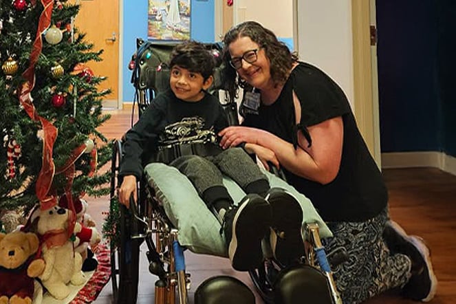 a child in a wheelchair smiling with a woman