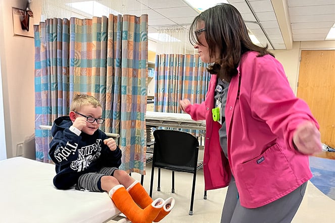 a seated child with two leg casts dancing with a standing adult