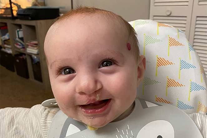 Charlie Gail eating solid food in highchair