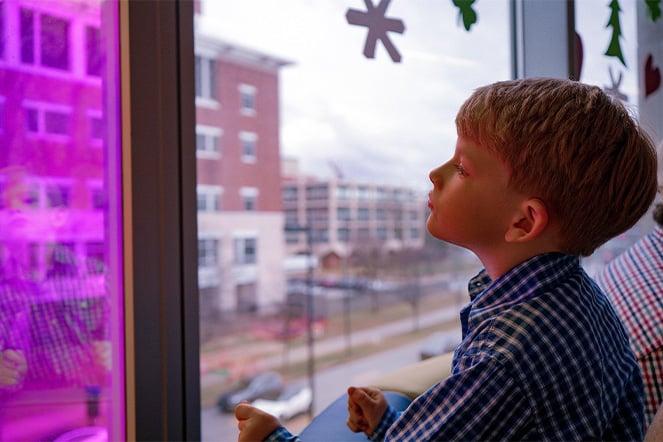 a child staring out the window looking at a brick building across the street