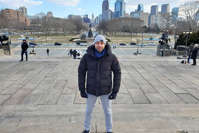 Chris standing on outside with Boston city behind him