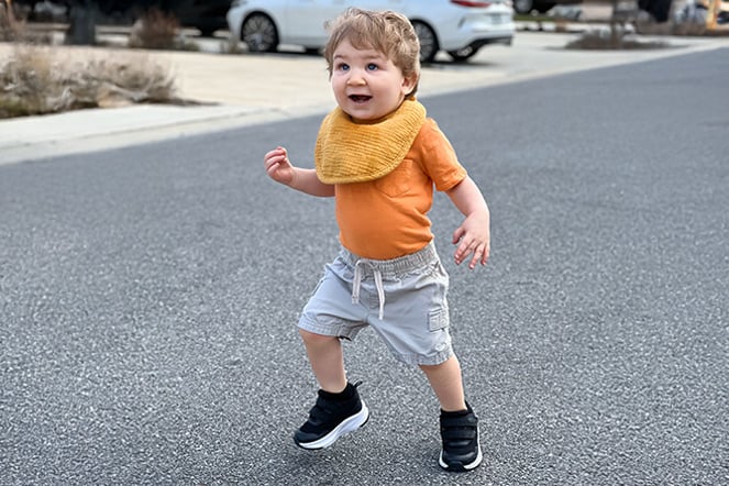 a toddler running on asphalt 