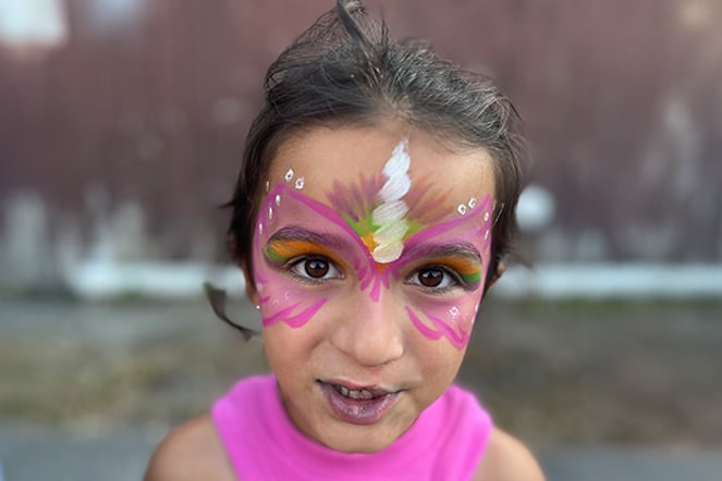 a young girl with her face painted like a unicon