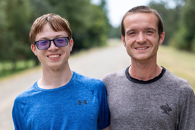 two teenage men standing side-by-side with one another
