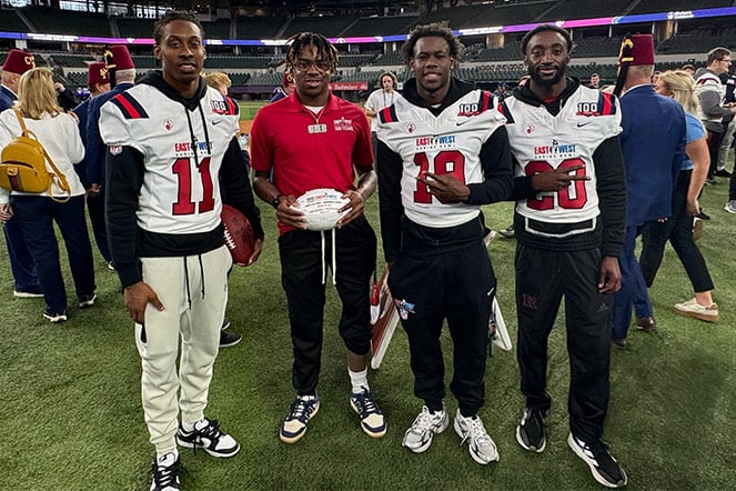 Clubfoot patient holding a football and smiling with 3 football players in jerseys