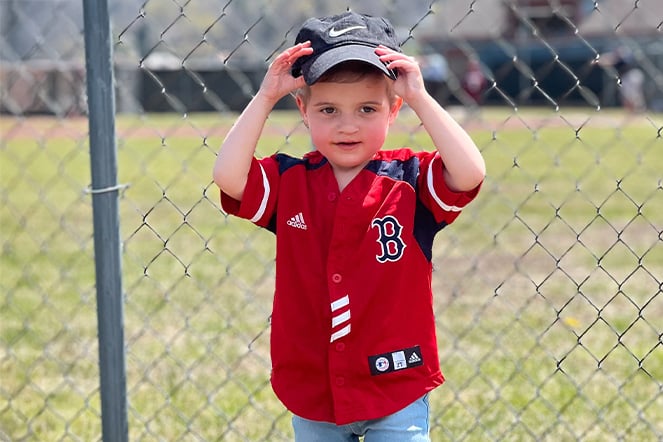 a child wearing a baseball jersey in front of a chain-link fence