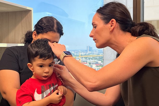 a small child being fitted for an ear device by two adults