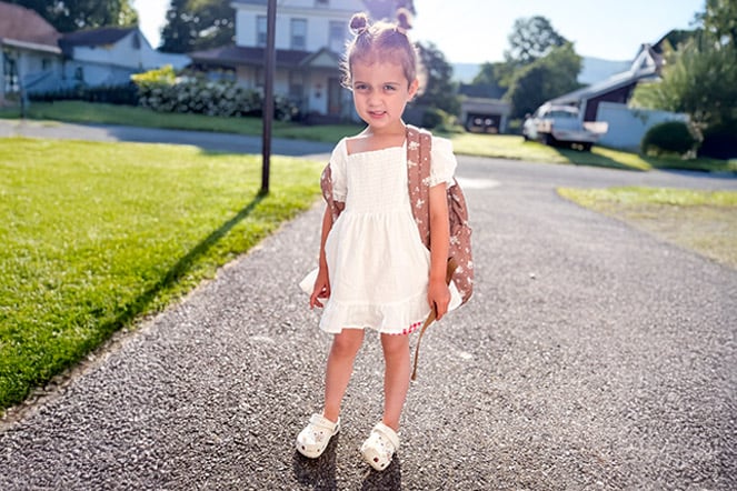 a child in a dress standing in a driveway