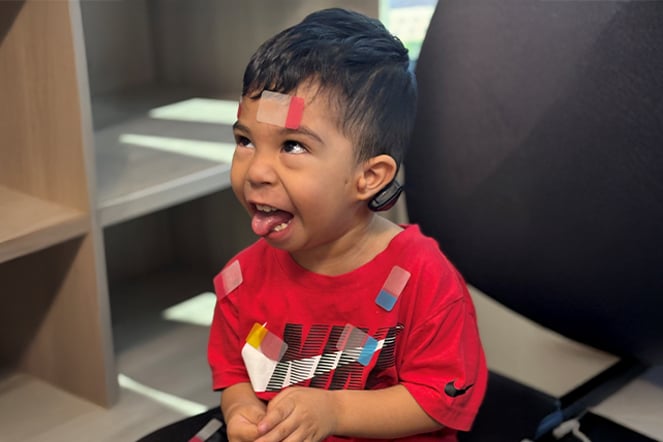 a child laughing and sticking out his tongue with his face and shirt covered in stickers