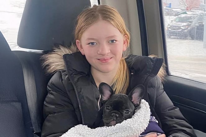 a young woman with a cleft surgery scar holding a small dog in a car